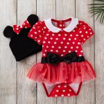 Red polka dot baby outfit with a white collar, black bow, and tutu; paired with a black hat with mouse ears and a bow.