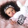 Baby lying on a fluffy pink blanket, holding a white stuffed bunny, wearing a headband and shirt printed "LIMITED EDITION," resembling the lifelike charm of reborn doll craftsmanship.